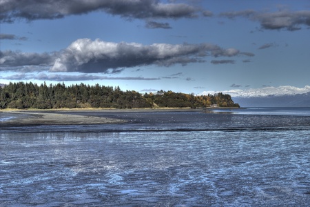 Mud bay at low tide with a finger of shoreline and puffy clouds.の写真素材
