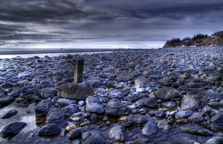Rocky beach in Alaska with storm clouds and calm water in the background.の写真素材