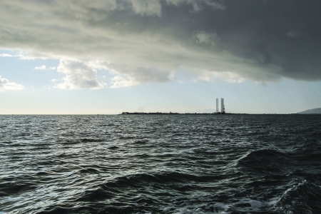 Large storm cloud hanging over a Jack-up oil drilling rig in the harbor at Homer Alaska.の写真素材