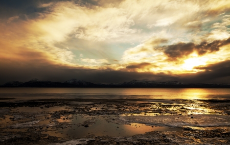 Dramatic winter sunset over the Kachemak Bay in Alaska with frozen ice and dramatic clouds.の写真素材