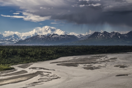 Mt. Denali (Mr. McKinley) in summer with a riverbed in the foreground and storm clouds moving in.の写真素材