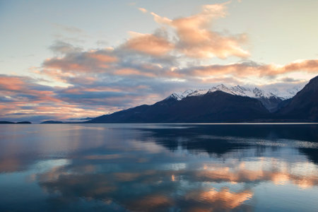 Sunset clouds reflected in still water of the Chilkat Inlet near Haines Alaska with snow capped...