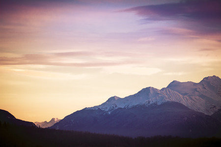 Sunset over snow capped mountains in Southeast Alaskaの写真素材