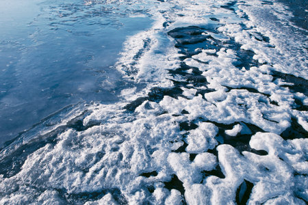 Patterns in ice and snow on the beach beside a frozen Alaskan river.