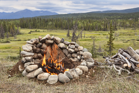 Campfire in a rock ring overlooking a valley view in the Yukon Territory of Canada in summer.の写真素材