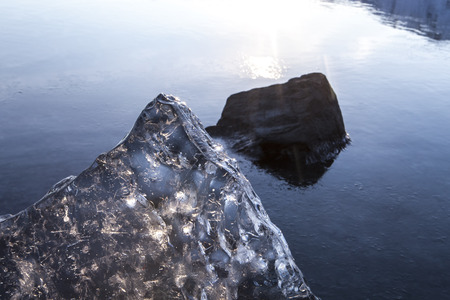 Large chunk of translucent sea ice on a beach in Southeast Alaska at sunset with an incoming tide.の写真素材