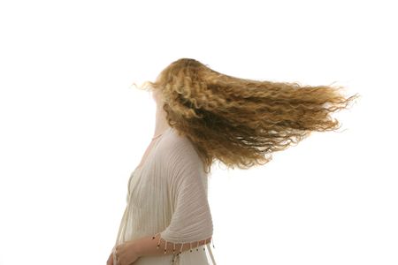 pretty young girl with long curly hair  in long withe dress  looking to the photographerの写真素材