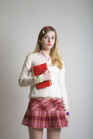 Sweet teenager school girl in pink mini skirt with red bookの写真素材