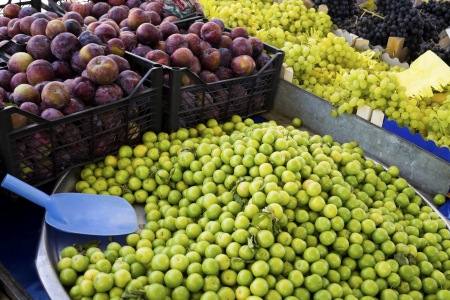 Green and red Plums with Grapes on market placeの写真素材