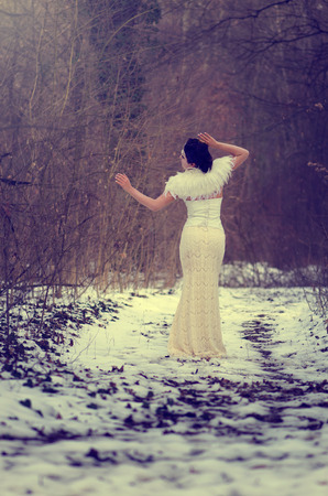 Beautiful bride in lace dress with a feather bolero posing in a forestの写真素材