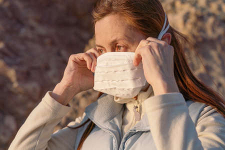 Masked redhead girl dressed in bright clothes outdoors on a sunny day. pandemicの写真素材