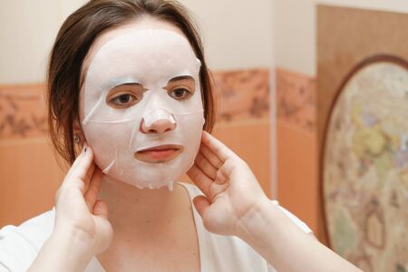 A cheerful and funny girl fooling around and grimacing in a moisturizing face mask. Morning beauty treatments, oily and combination skin care conceptの写真素材