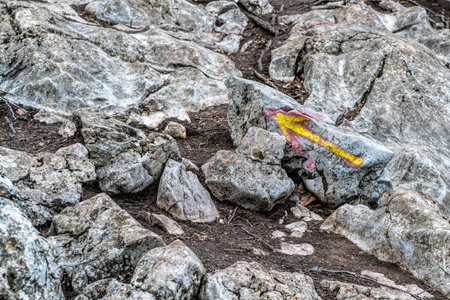 Hiking trail. A grey rocky road up the mountain with a yellow arrow drawn to indicate the way....