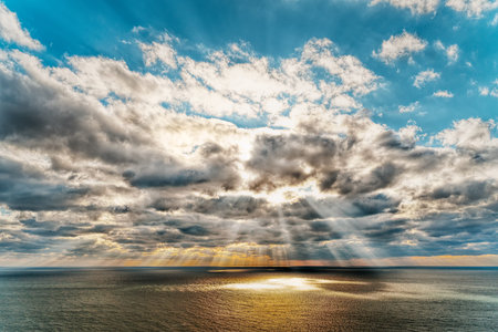 Beautiful sunset over the sea with reflection in the water, majestic clouds in the sky. Golden...