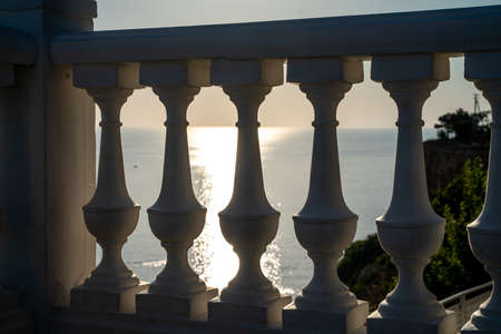 Classic balustrade on the embankment against the sea. White balcony over the sea. Promenade with a beautiful view of the sea on a clear day. Close-up of the balustrade by the seaの写真素材