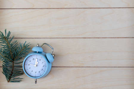 Christmas fir branches and blue retro alarm clock on wooden striped background, good for New Year backgroundの写真素材