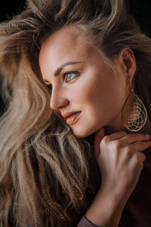 Profile of a beautiful blonde with green eyes, light makeup, large earring in the ear.の写真素材
