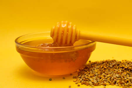 A ladle of honey on the background of a honeycomb of a bee. Honey tidbit in a glass jar spoon for honey, bee bread and a honeycomb made of wax.の写真素材