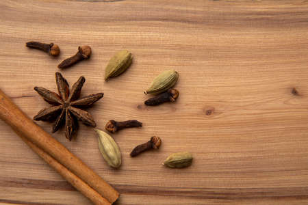 Cinnamon, cloves, star anise and cardamom pods on a wooden table.の写真素材
