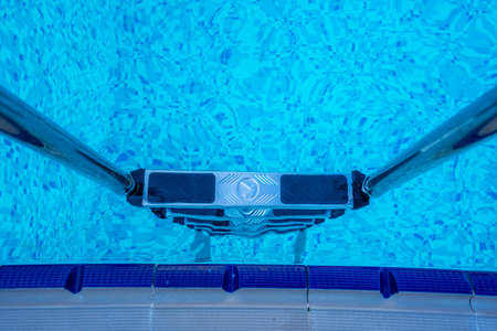 Background of blue transparent water in the swimming pool on the territory of the hotel. Descent to the pool with handrails. Rest and relaxation concept. Active rest by the seaの写真素材