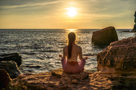 Young woman practicing yoga outdoors. Harmony and meditation concept. Healthy lifestyleの写真素材