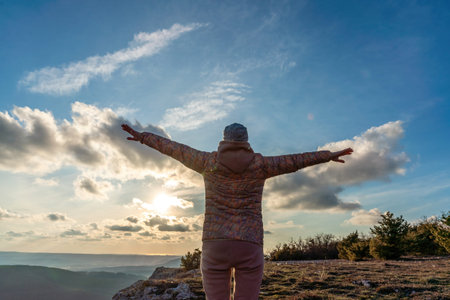 The girl at sunset. The girl stands with her back on the top of the mountain and looks at the...