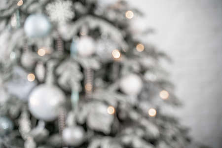 Close-up of a festively decorated outdoor Christmas tree with balls on a blurred sparkling fairy background. Defocused garland lights, bokeh effect.の写真素材