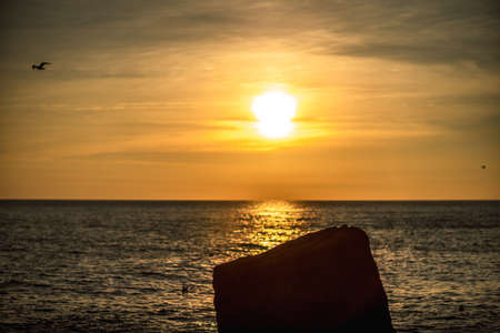 Golden sunset in the sea stone in the foreground.の写真素材