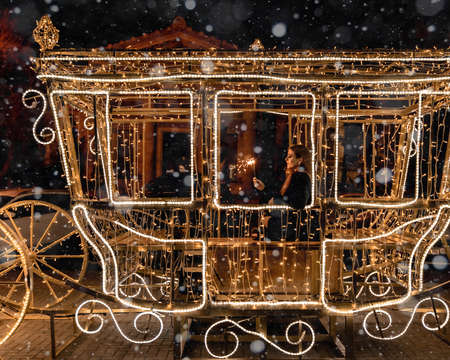 The girl sits in a beautiful New Years carriage in the lights. Oda holds sparklers in her hands.の写真素材
