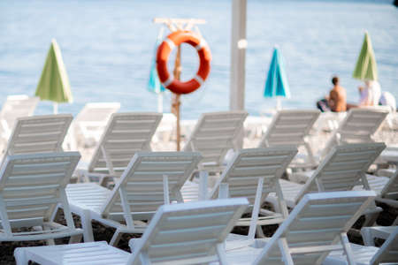 Several white sun loungers and an umbrella on a deserted beach. The perfect vacation concept.の写真素材
