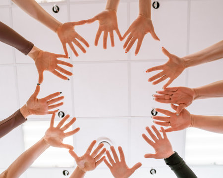 Team of people holding hands. Group of happy young women holding hands. Bottom view, low angle shot of human hands. Friendship and unity conceptの写真素材