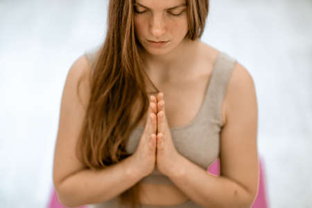 Girl does yoga. Young woman practices asanas on a beige one-ton background.の写真素材