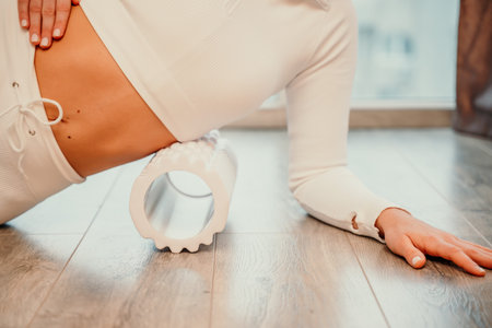 Adult athletic woman, in white bodysuit, performing fascia exercises on the floor - caucasian woman...
