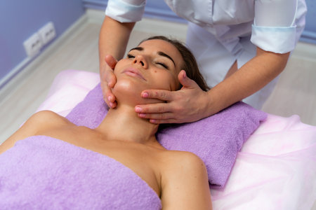 Relaxing massage. European woman getting facial massage in spa salon, side viewの写真素材