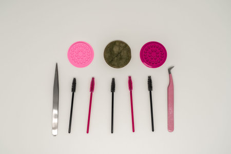 Eyelash extension tools, eyelash combs and eyelashes on a white background.