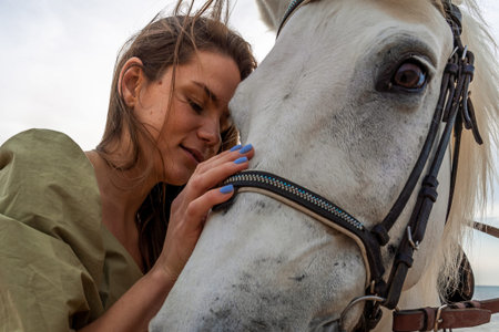 A young woman and a white horse against the background of the sky and the sea.