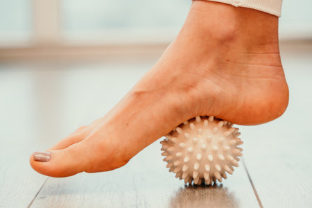 Athletic slim caucasian woman doing thigh self-massage with a massage ball indoors. Self-isolating massageの写真素材