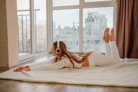 Side view portrait of relaxed woman listening to music with headphones lying on carpet at home. She...