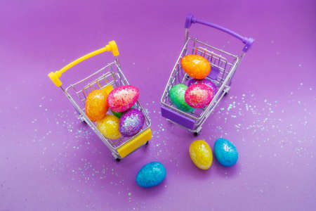 Happy Easter background. Easter eggs are colorful in a shopping basket on purple paper. Holiday concept. Copy space for text.の写真素材
