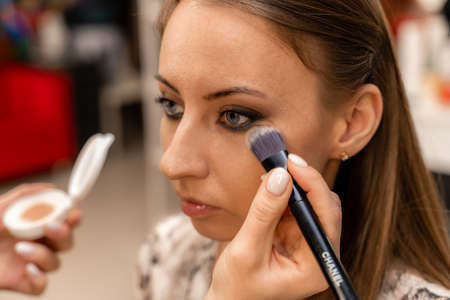 Make-up artist working with brush on model eyes Close up of applying make up on young girl,semi profile, professional make up in beauty studioの写真素材