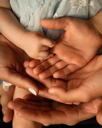 Close up of loving mom dad and kid hold hands on floor palms up together express closeness and unity, caring parents join stack arms with child show devotion, support and bonding. Family value conceptの写真素材