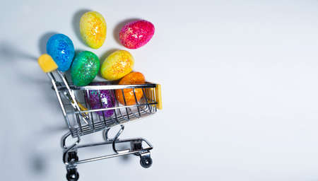 Happy Easter background. Easter colorful eggs in a shopping basket on a white background. Holiday concept. Copy space for text.の写真素材