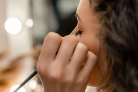 Make-up artist makes a professional make-up of a young woman in the studio.の写真素材