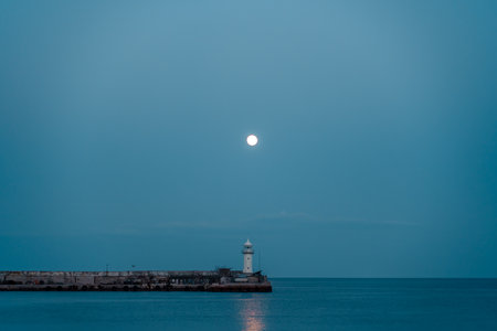 The full moon rises to the lighthouse, the moon path is not the sea.の写真素材