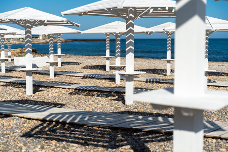 Rows of wooden umbrellas from the sun on the seashore in the morning. Wooden paths on the sand between umbrellas. Beach holiday at the resort.の写真素材