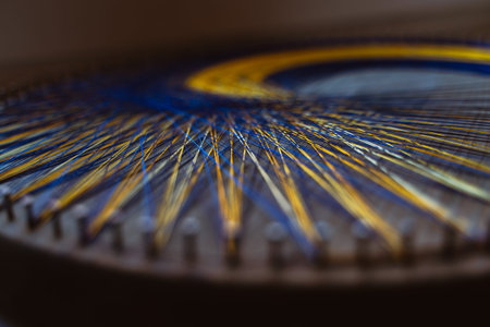 Colored thread mandala on a wooden board with nails. Mandala Moon Harmony Sun esotericism and...