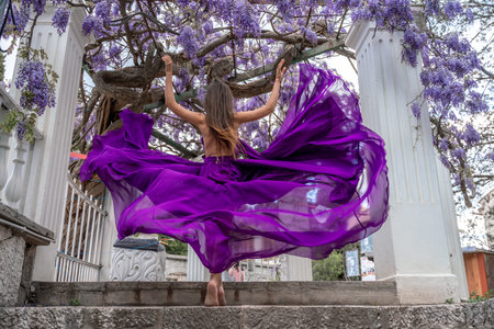 Woman wisteria purple dress. Thoughtful happy mature woman in purple dress surrounded by chinese...