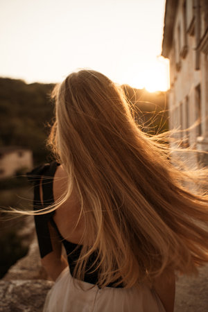 Blonde long hair, nature summer happy adult girl with long blond hair developing in the wind in nature. Dressed in a black top, white skirt.の写真素材