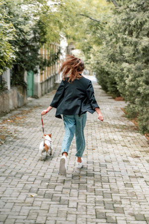 A girl and a boy are walking with a Jack Russell Terrier, walking down the streetの写真素材