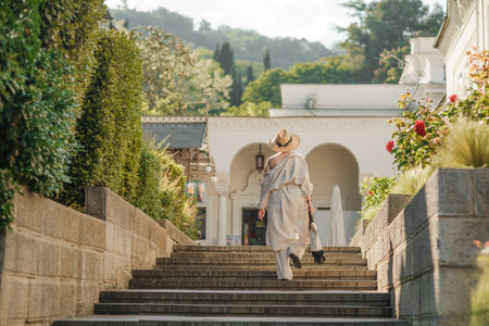 Woman on the stairs in the park. A middle-aged lady in a hat in a white outfit with a bag walks around the Livadia Palaceの写真素材